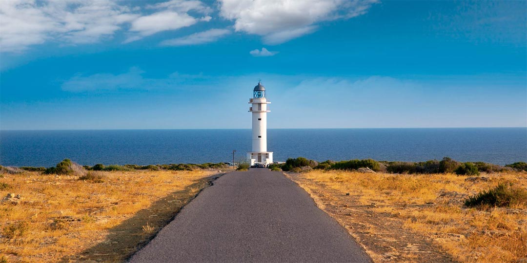 Vista della strada che porta al Faro di Es Cap de Barbaria con il mare sullo sfondo.